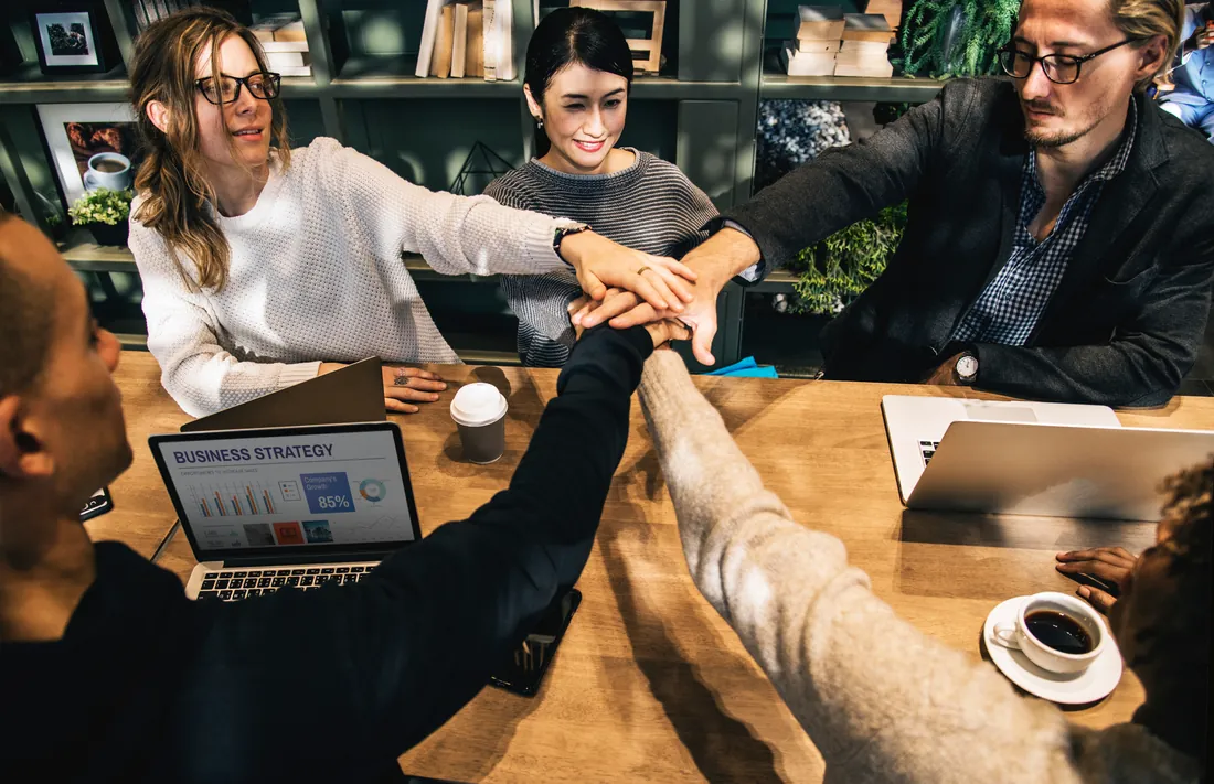 A team joining hands over a table