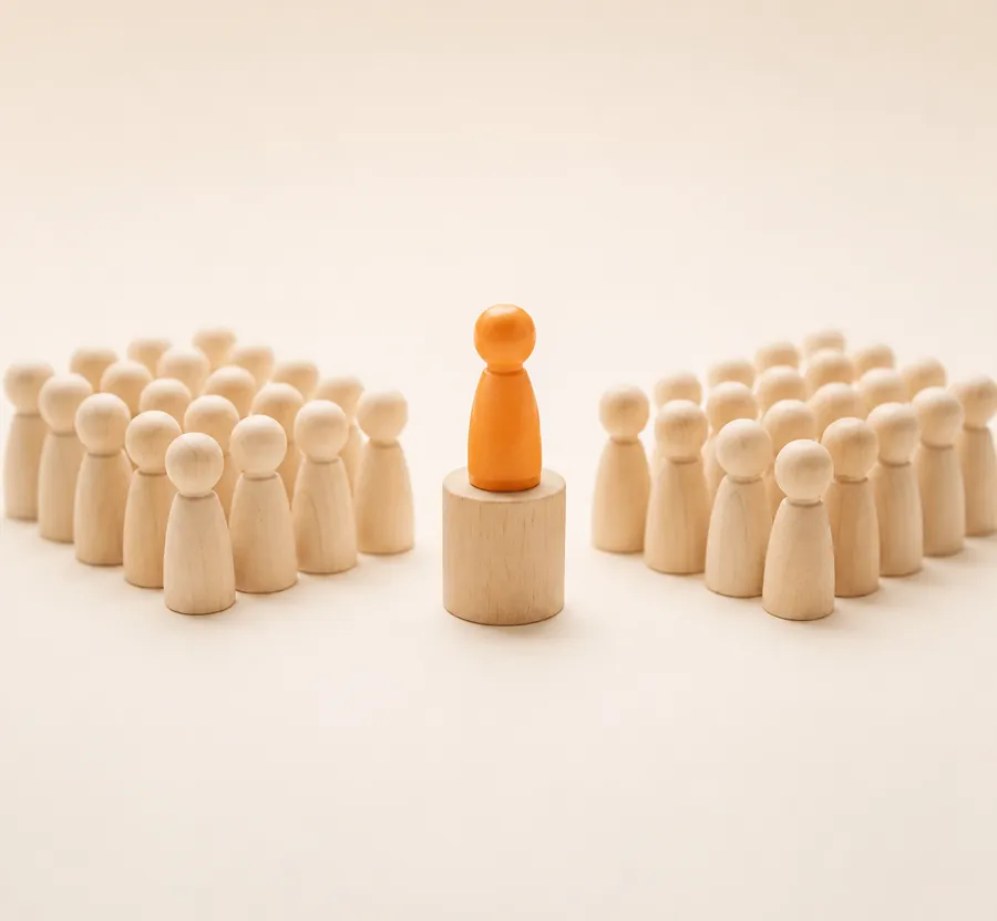 A single orange wooden figure standing out among a crowd of plain wooden figures