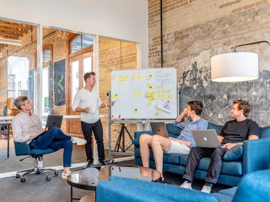 A colleague walking a small team through a plan laid out in sticky notes on a whiteboard